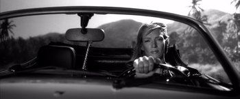 Movie still from “Kill Bill: Vol. 2” (2004), directed by Quentin Tarantino – A black and white photo of a woman driving a car; Close Up shot, Low angle