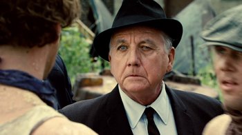 Movie still from “Kill the Irishman” (2011), directed by Jonathan Hensleigh – An older man wearing a black hat and a suit; Close Up shot, Over the shoulder angle