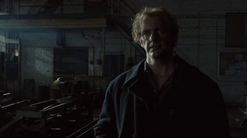 Movie still from “Kill the Irishman” (2011), directed by Jonathan Hensleigh – A man standing in a dark room next to a train track; Medium shot, Low angle