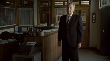 Movie still from “Kill the Irishman” (2011), directed by Jonathan Hensleigh – An older man in a suit standing in front of an old typewriter; Medium shot, Low angle