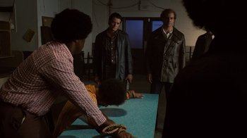 Movie still from “Kill the Irishman” (2011), directed by Jonathan Hensleigh – A group of people standing around a table; Medium shot, Over the shoulder angle