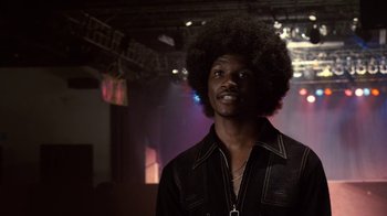 Movie still from “Kill the Irishman” (2011), directed by Jonathan Hensleigh – A man in a black shirt with a black afro is looking at the camera; Close Up shot, Low angle