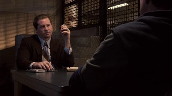 Movie still from “Kill the Irishman” (2011), directed by Jonathan Hensleigh – A man sitting at a table in front of a cell phone; Medium shot, Over the shoulder angle