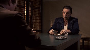 Movie still from “Kill the Irishman” (2011), directed by Jonathan Hensleigh – A man sitting at a table with a cell phone; Medium shot, Over the shoulder angle