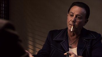 Movie still from “Kill the Irishman” (2011), directed by Jonathan Hensleigh – A man smoking a cigarette while sitting in a chair; Close Up shot, Over the shoulder angle