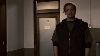 Movie still from “Kill the Irishman” (2011), directed by Jonathan Hensleigh – A man standing in front of a door in a room; Medium shot, Low angle