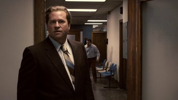 Movie still from “Kill the Irishman” (2011), directed by Jonathan Hensleigh – A man in a suit and tie standing in an office hallway; Medium shot, Over the shoulder angle