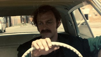 Movie still from “Kill the Irishman” (2011), directed by Jonathan Hensleigh – A man driving a car in the middle of the day; Close Up shot, Low angle