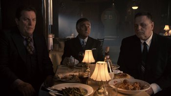 Movie still from “Kill the Irishman” (2011), directed by Jonathan Hensleigh – A man sitting at a dinner table in a suit; Medium shot, High angle