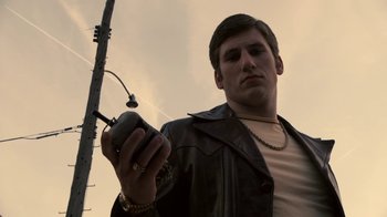 Movie still from “Kill the Irishman” (2011), directed by Jonathan Hensleigh – A man holding a cell phone while standing under a street light; Close Up shot, Low angle