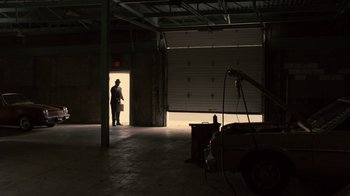 Movie still from “Kill the Irishman” (2011), directed by Jonathan Hensleigh – A man standing in a room with a garage door open; Wide shot, Low angle