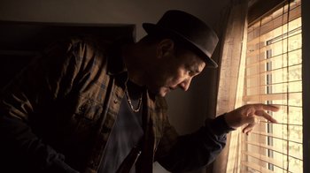 Movie still from “Kill the Irishman” (2011), directed by Jonathan Hensleigh – A man wearing a hat looking out of a window; Medium shot, Low angle