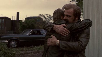 Movie still from “Kill the Irishman” (2011), directed by Jonathan Hensleigh – A man and a woman hugging in front of a car; Medium shot, Low angle
