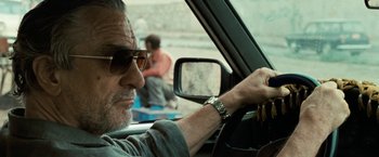Movie still from “Killer Elite” (2011), directed by Gary McKendry – A person in a car; Close Up shot, Over the shoulder angle
