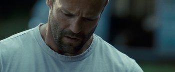 Movie still from “Killer Elite” (2011), directed by Gary McKendry – A person wearing a white t - shirt; Close Up shot, Low angle