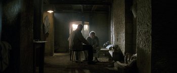 Movie still from “Killer Elite” (2011), directed by Gary McKendry – Two men are sitting in a dimly - lit room; Wide shot, Over the shoulder angle