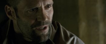 Movie still from “Killer Elite” (2011), directed by Gary McKendry – A person with a beard; Close Up shot, Over the shoulder angle