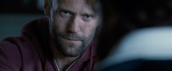 Movie still from “Killer Elite” (2011), directed by Gary McKendry – A person with a beard looking at the camera; Close Up shot, Over the shoulder angle