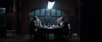 Movie still from “Killer Elite” (2011), directed by Gary McKendry – A group of people sitting at a table in a room; Wide shot, Low angle