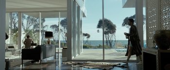 Movie still from “Killer Elite” (2011), directed by Gary McKendry – A living room with large windows overlooking the ocean; Extreme Wide shot, High angle