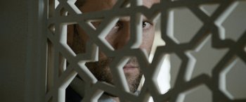 Movie still from “Killer Elite” (2011), directed by Gary McKendry – A man's face through a fence; Close Up shot, Low angle