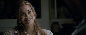 Movie still from “Killer Elite” (2011), directed by Gary McKendry – A woman smiling for the camera with long hair; Close Up shot, Over the shoulder angle