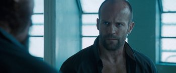 Movie still from “Killer Elite” (2011), directed by Gary McKendry – A man with a beard is looking at the camera; Close Up shot, Low angle