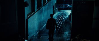 Movie still from “Killer Elite” (2011), directed by Gary McKendry – A man walking down the side of a street at night; Wide shot, High angle