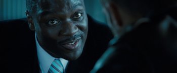 Movie still from “Killer Elite” (2011), directed by Gary McKendry – A person wearing a suit and tie; Close Up shot, Over the shoulder angle