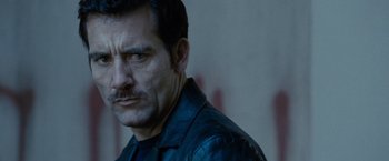 Movie still from “Killer Elite” (2011), directed by Gary McKendry – A person wearing a leather jacket; Close Up shot, Over the shoulder angle