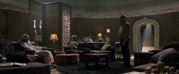 Movie still from “Killer Elite” (2011), directed by Gary McKendry – Two men are sitting on a couch in a living room; Wide shot, Over the shoulder angle