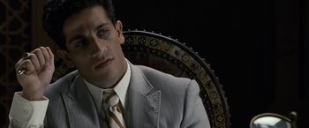 Movie still from “Killer Elite” (2011), directed by Gary McKendry – A man wearing a suit and tie sitting in a chair; Close Up shot, High angle