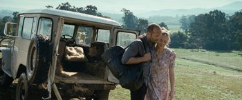 Movie still from “Killer Elite” (2011), directed by Gary McKendry – A man and a woman walking in front of an old truck; Wide shot, Over the shoulder angle