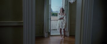 Movie still from “Killer Elite” (2011), directed by Gary McKendry – A woman standing in front of an open door; Wide shot, Low angle