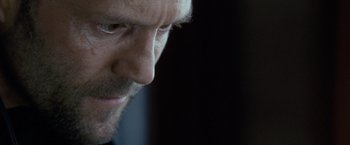 Movie still from “Killer Elite” (2011), directed by Gary McKendry – A man's face in a dark room; Extreme Close Up shot, Over the shoulder angle