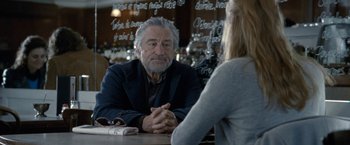 Movie still from “Killer Elite” (2011), directed by Gary McKendry – An older man sitting at a table talking to a young woman; Medium shot, Over the shoulder angle