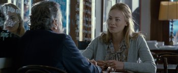 Movie still from “Killer Elite” (2011), directed by Gary McKendry – A woman sitting at a table talking to an older man; Close Up shot, Over the shoulder angle