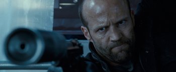 Movie still from “Killer Elite” (2011), directed by Gary McKendry – A person with a gun in his hand; Close Up shot, Low angle