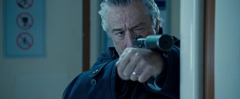 Movie still from “Killer Elite” (2011), directed by Gary McKendry – An older man is holding a gun in his hand; Close Up shot, Over the shoulder angle
