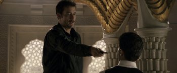 Movie still from “Killer Elite” (2011), directed by Gary McKendry – A man is pointing at something while another man looks at him; Medium shot, Over the shoulder angle