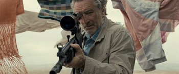 Movie still from “Killer Elite” (2011), directed by Gary McKendry – An older man looking through a rifle scope; Close Up shot, Over the shoulder angle