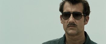 Movie still from “Killer Elite” (2011), directed by Gary McKendry – A person wearing sunglasses; Close Up shot, Low angle