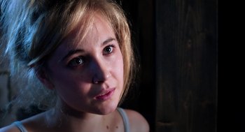 Movie still from “Killer Joe” (2011), directed by William Friedkin – A young woman's face in the dark; Close Up shot, Over the shoulder angle