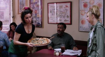 Movie still from “Killer Joe” (2011), directed by William Friedkin – A woman serving a pizza to a man at a restaurant; Medium shot, Over the shoulder angle
