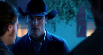 Movie still from “Killer Joe” (2011), directed by William Friedkin – A man wearing a cowboy hat in a dark room; Close Up shot, Over the shoulder angle