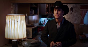 Movie still from “Killer Joe” (2011), directed by William Friedkin – A man wearing a cowboy hat in a kitchen; Medium shot, Over the shoulder angle