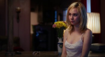 Movie still from “Killer Joe” (2011), directed by William Friedkin – A beautiful young lady sitting in front of a vase of yellow flowers; Close Up shot, Over the shoulder angle