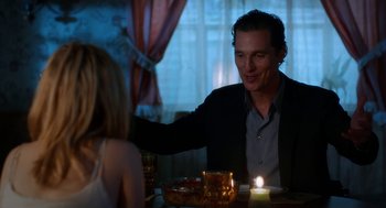 Movie still from “Killer Joe” (2011), directed by William Friedkin – A man sitting at a dinner table with a candle in front of him; Medium shot, Over the shoulder angle