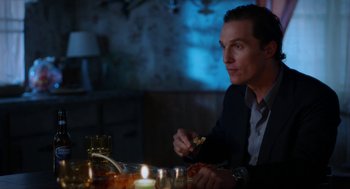 Movie still from “Killer Joe” (2011), directed by William Friedkin – A man sitting at a dinner table eating pizza; Medium shot, Over the shoulder angle