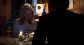 Movie still from “Killer Joe” (2011), directed by William Friedkin – A woman sitting at a dinner table with a candle; Medium shot, Over the shoulder angle